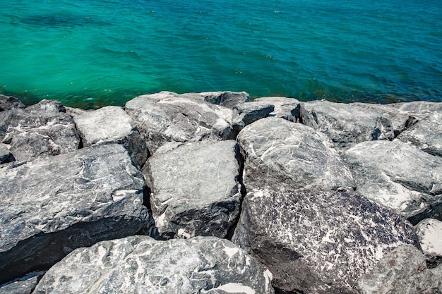 Foto grandes pedregulhos pedras quebra-mares no mar com água turquesa
