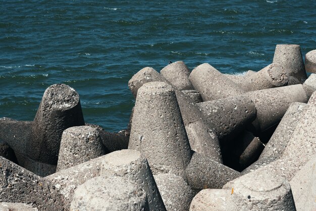 Grandes piedras se encuentran en la playa frente a las olas.