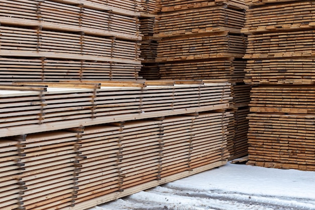 Grandes pilas de fondo de tablones de madera con enfoque selectivo y perspectiva lineal al aire libre de invierno
