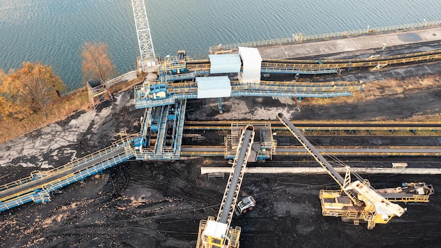 Grandes pilhas de carvão, vista superior. Armazenamento de carvão na TPP, descarga e carregamento de carvão por escavadeiras e correias de transporte no armazém da TPP. Fotografia aérea