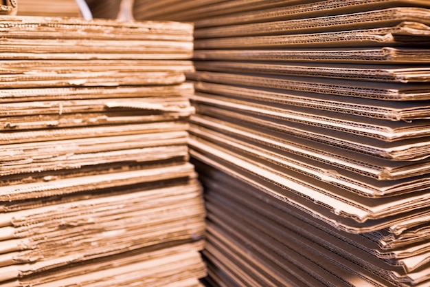 Grandes pilhas de papelão em close-up ficam uma em cima da outra em um depósito. conceito de armazenamento de coisas e materiais ecológicos. conceito de material renovável