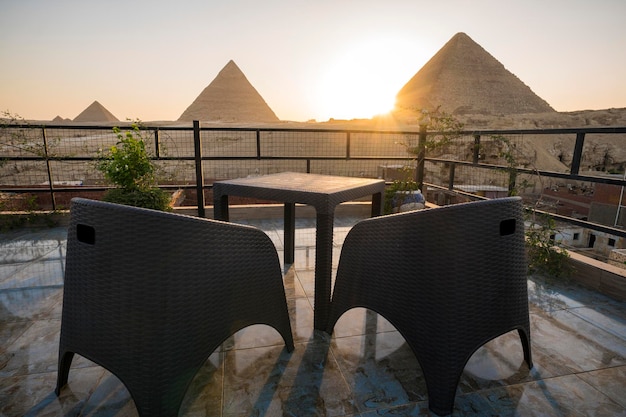 Grandes Pirâmides de Chephren Khafra e Cheops Khufu e Mikerina Menkaura Pôr do sol no planalto de Gizé o sol se põe abaixo do horizonte restaurante na cobertura no Cairo com bela vista do marco Cairo Egito