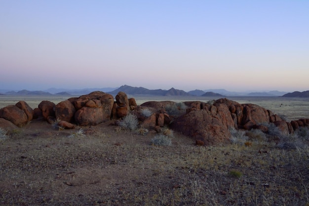 Grandes rocas contra el cielo nocturno en el paisaje desértico con montañas rocosas lejanas Entorno árido