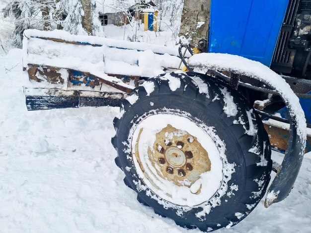 Grandes rodas de um trator azul em uma floresta de neve