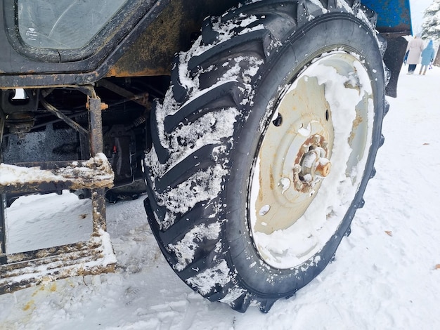 Grandes rodas de um trator azul em uma floresta de neve