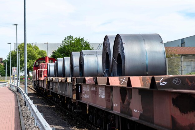 Foto grandes rollos de chapa metálica en un vagón de mercancías tirado por locomotoras