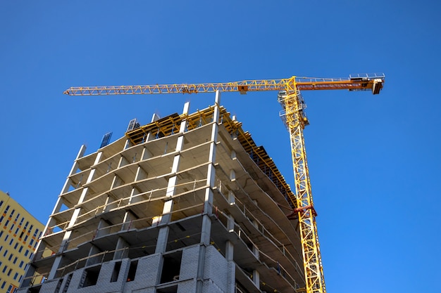 Los grandes sitios de construcción y la grúa amarilla están funcionando, concepto de negocio de nuevos edificios de la industria, fondo de cielo azul