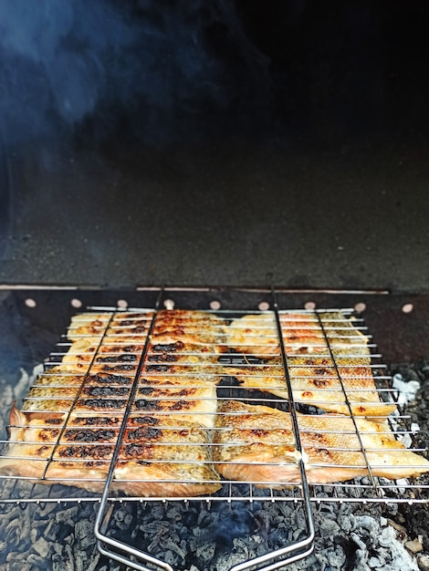 Grandes trozos de pescado rojo se cocinan en leña, salmón a la parrilla, comida sana y fragante al aire libre.