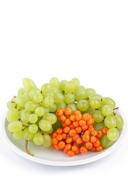 Grandes uvas dulces sabrosas y serbas en un primer plano de la placa blanca Racimo de uvas jugosas verdes y serbas aisladas sobre fondo blanco