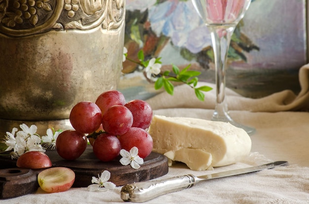 Grandes uvas rosadas sobre la mesa Queso de cabra de granja Cubiertos antiguos Un cuchillo vintage