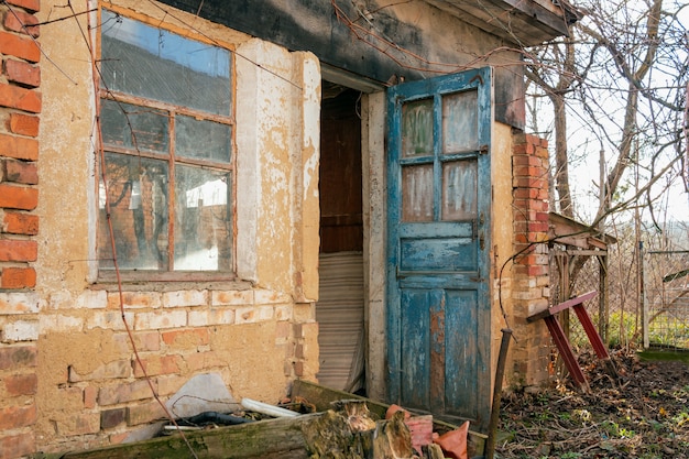 Granero de ladrillo o granja abandonada de estilo retro con puertas azules abiertas y ventana grande en la aldea,