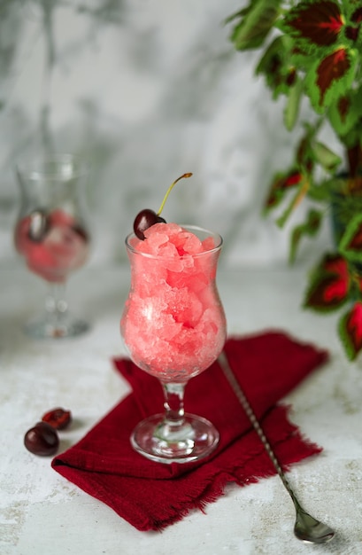 Granizado de cereza - desierto de verano - primer plano y bebida refrescante con hielo sobre un fondo gris claro