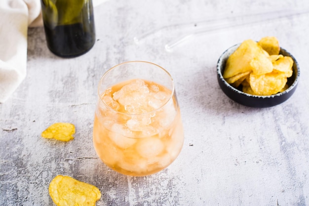 Granizado de cerveza en un vaso y papas fritas en un tazón sobre la mesa Bebida de verano de moda