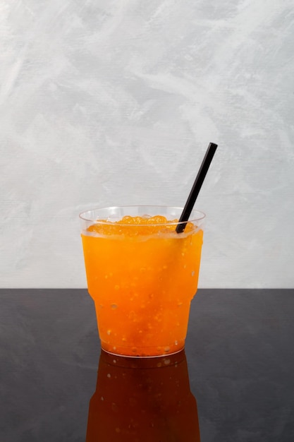 Granizado de cítricos o granizado de naranja en vaso de plástico. Hielo raspado de frutas. Refrescante bebida granizada.