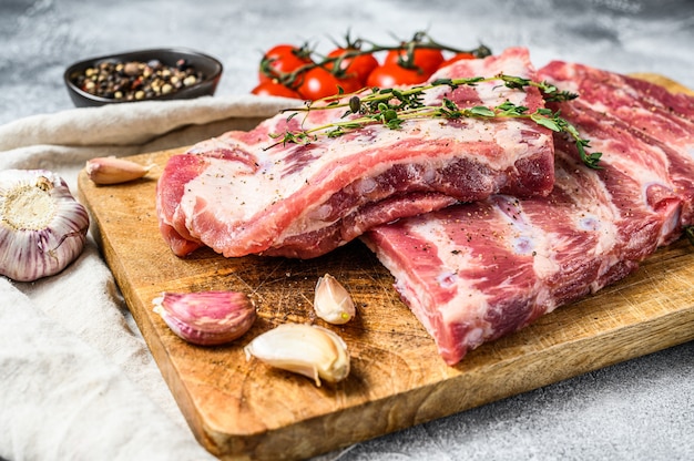 Granja de carne orgánica. Costillas de cerdo crudas con romero, pimienta y ajo. Pared gris. Vista superior