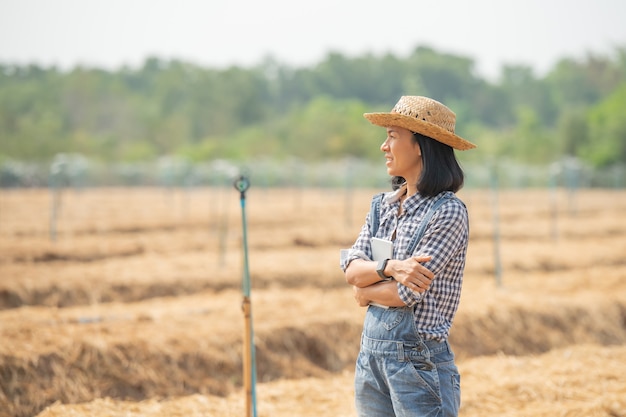 Granja inteligente. Hermoso agricultor usa tableta para controlar su granja y negocio con felicidad y sonrisa. Concepto de agricultura y negocios. El agricultor o el agrónomo examinan preparar una parcela para cultivar hortalizas.