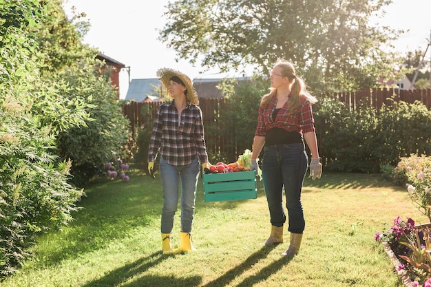 Granjera sosteniendo verduras orgánicas maduras en caja de madera en el jardín copyspace Mujer feliz jardinero cosechando productos agrícolas para la venta en línea