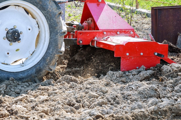 Granjero ara el campo. Pequeño tractor con arado en el campo. Cultivo.