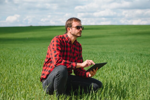 Granjero feliz en los campos con una computadora portátil