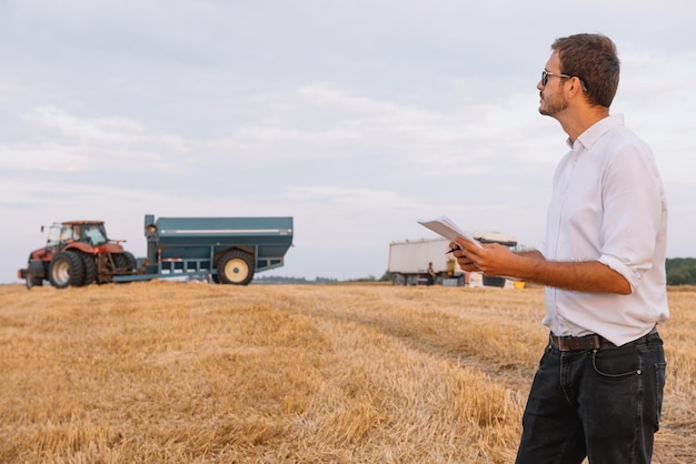 Granjero feliz de pie en un campo de trigo después de la cosecha. Concepto de agricultura