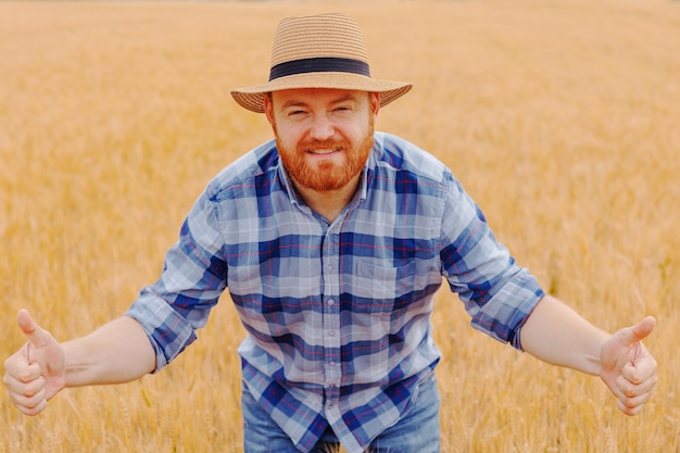 Granjero feliz Planta de pie en su campo de trigoGranjero campesino de pie cultivando trigo en el campo con habilidad y cuidado