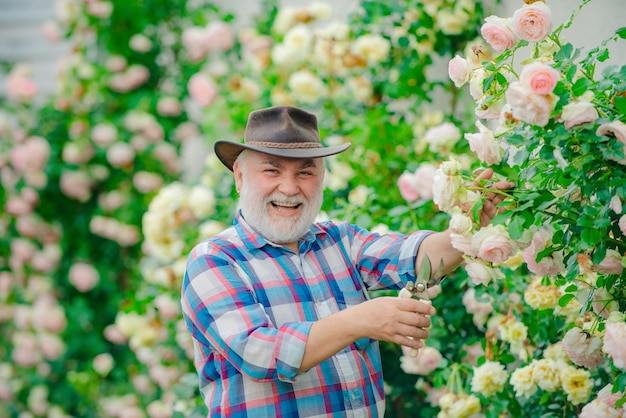 Granjero feliz con sombrero de vaquero divirtiéndose en el campo abuelo en un hermoso jardín abuelo disfrutando