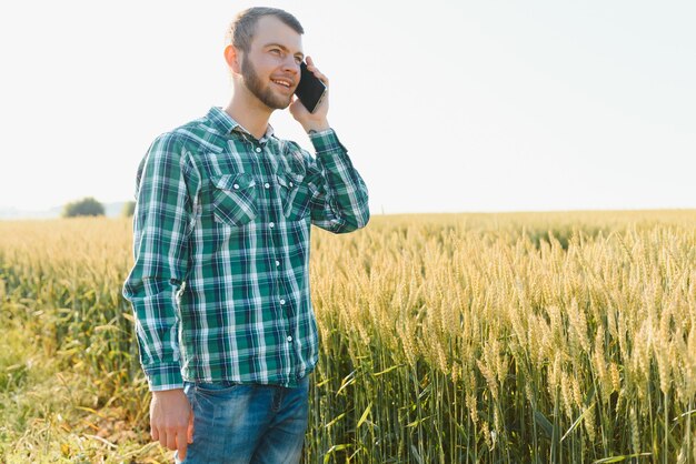 Granjero hablando por teléfono móvil en el campo en un día soleado