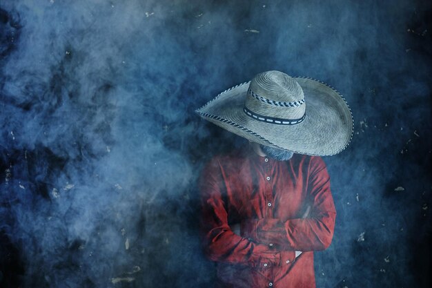 granjero hipster en un sombrero de paja con ala en humo fumar tabaco estilo retro salvaje oeste sambrero