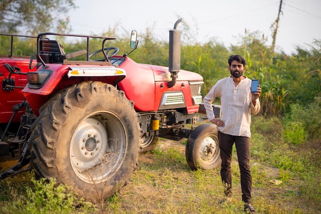 Granjero indio feliz con tractor en campo agrícola