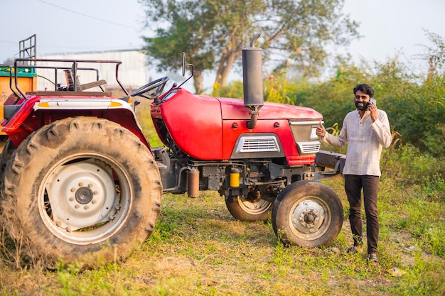 Granjero indio feliz con tractor en campo agrícola