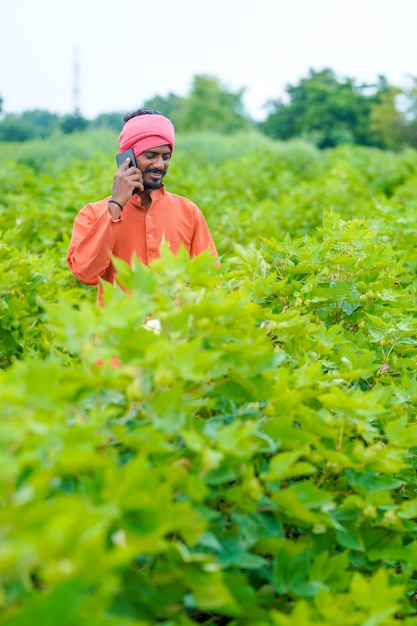 Granjero indio hablando por teléfono inteligente en el campo agrícola