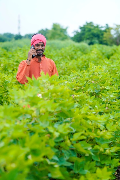 Granjero indio hablando por teléfono inteligente en el campo agrícola