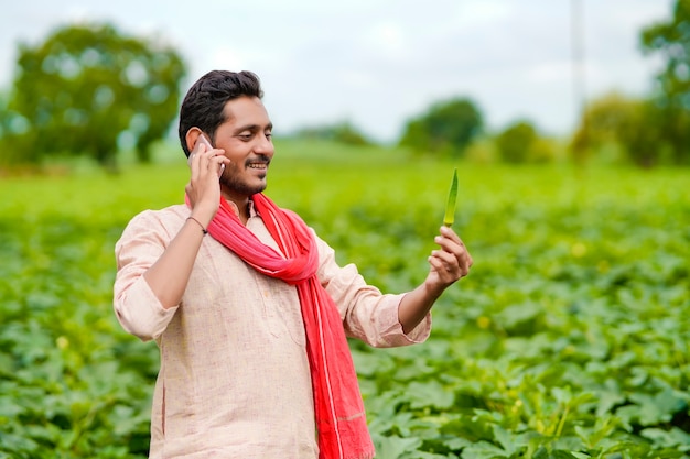 Granjero indio hablando por teléfono inteligente en el campo de la agricultura.