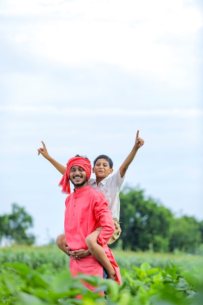 Granjero indio jugando con su hijo en el campo verde