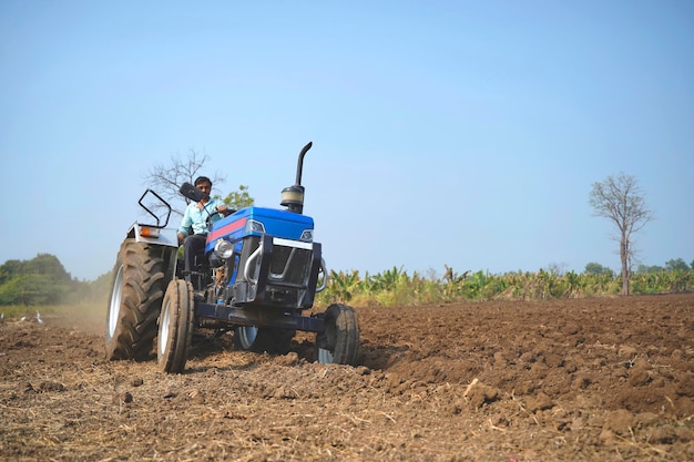 Granjero indio que trabaja con tractor en el campo agrícola.