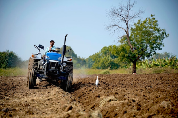 Granjero indio que trabaja con tractor en el campo agrícola.