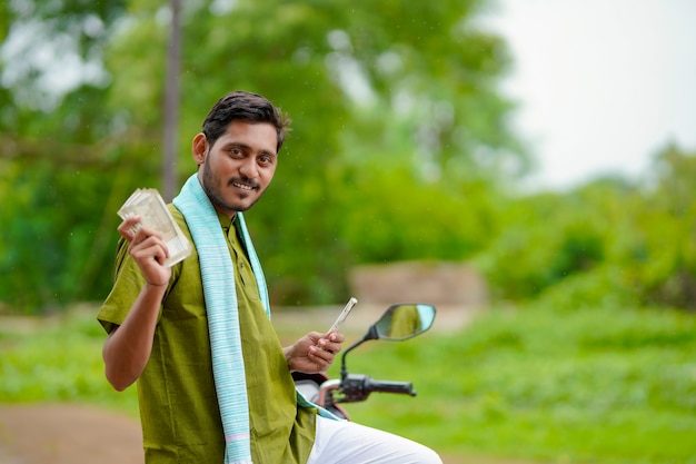 Granjero indio sentado en su nueva bicicleta y mostrando dinero.