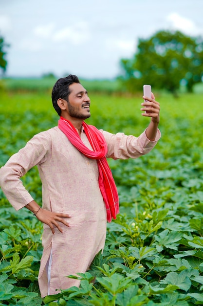 Granjero indio con smartphone en el campo de la agricultura.