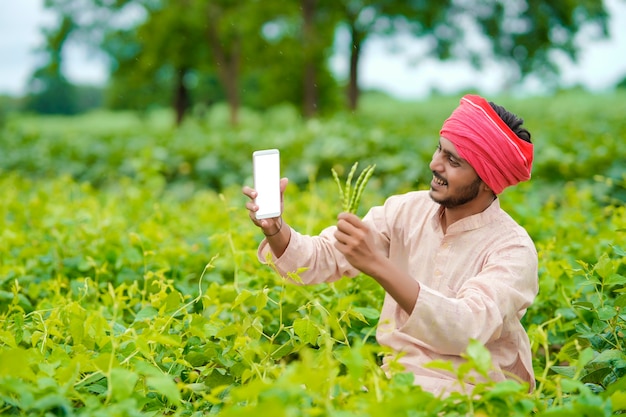 Granjero indio con smartphone en el campo de la agricultura.