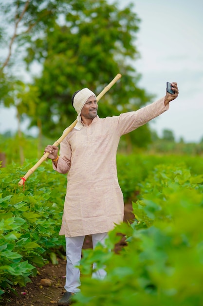 Granjero indio tomando selfie en campo de agricultura verde.