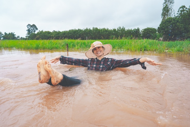 Granjero jugando y alegre en las fuertes inundaciones en los campos de arroz de las zonas rurales o rurales