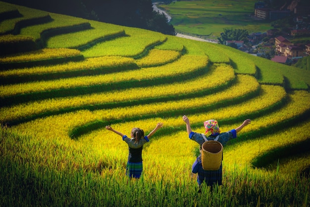 Granjero de mujeres e hija levantando el brazo en Campos de arroz aterrazados al atardecer en Mu Cang Chai