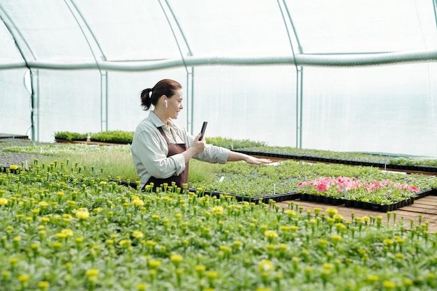 Granjero profesional con smartphone dando curso en línea sobre cultivo de flores