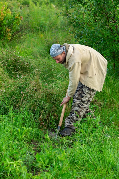 Foto granjero que trabaja en el jardín con su pala.