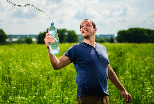 Granjero sediento cansado está bebiendo agua en el campo durante el descanso de la actividad agrícola