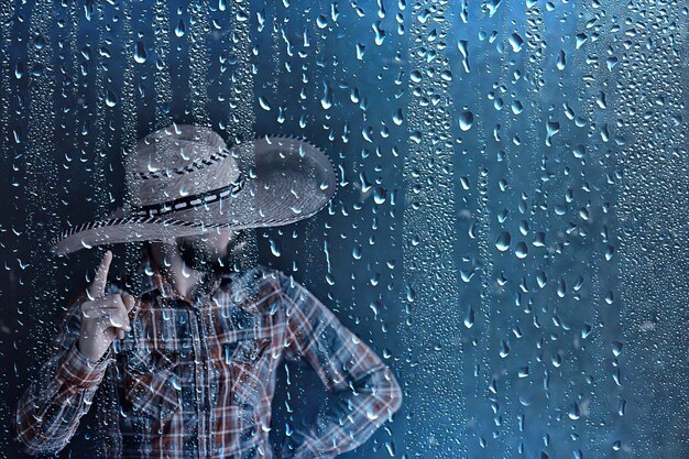 granjero con sombrero de paja detrás de gotas de lluvia de vidrio, clima estacional del salvaje oeste de América