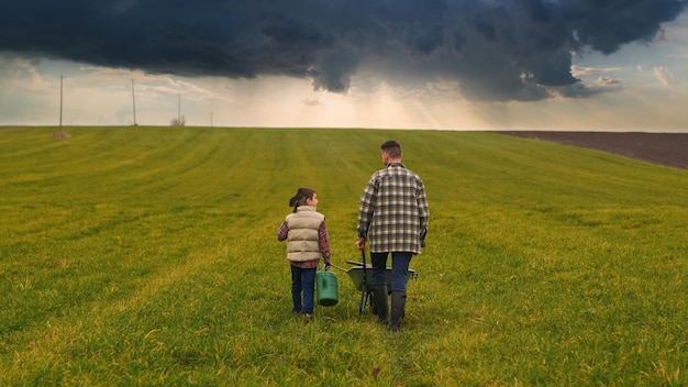 El granjero con su pequeño hijo caminando por el campo verde