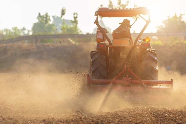 Granjero tailandés en gran tractor en la tierra para preparar el suelo