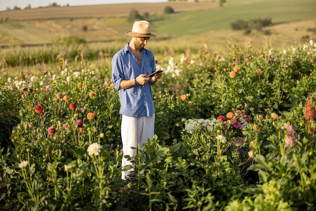 Granjero con teléfono en la granja de flores al aire libre