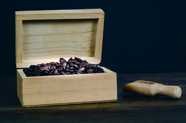 Grano de café en caja de madera sobre fondo de madera vieja.